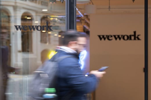 bloomberg-pedestrian-walks-past-wework-co-working-office-space-371999043-scaled-e1622032816829-1536x1024